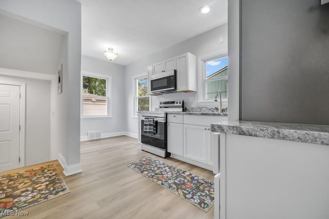 2186 Jackson Blvd, University Heights, OH 44118 - kitchen with stainless steel appliances, white cabinetry, light wood-style floors, light stone countertops, and baseboards