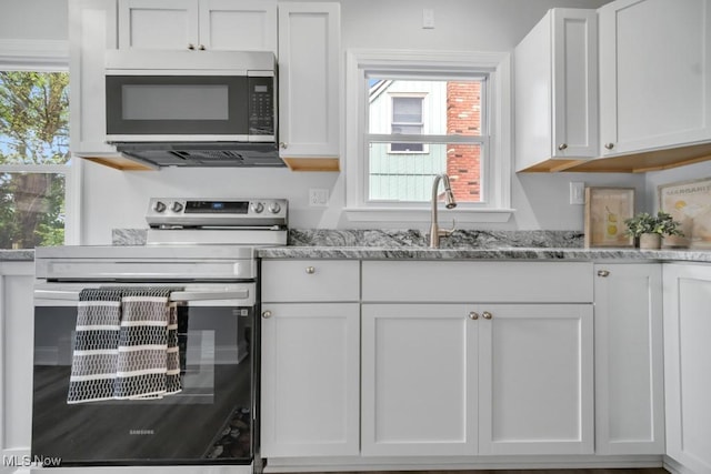 2186 Jackson Blvd, University Heights, OH 44118 - kitchen with stainless steel range with electric cooktop, white cabinetry, light stone counters, and a sink