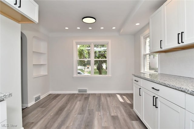 3890 Grosvenor Rd, South Euclid, OH 44118 - kitchen with light wood-type flooring, recessed lighting, light stone counters, white cabinetry, and decorative backsplash