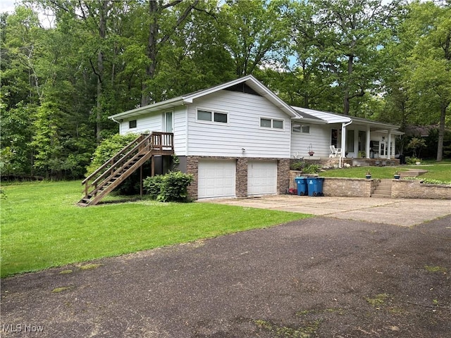 505 Woodside St SW, Hartville, OH 44632 - view of front facade with a garage, a front yard, stairs, concrete driveway, and covered porch