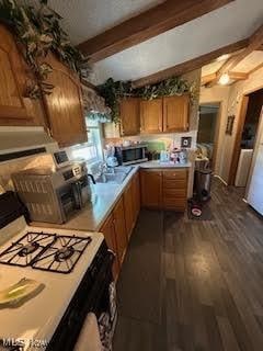 8452 E Bay Shore Rd Unit 7, Danbury, OH 43440 - kitchen with white range with gas stovetop, beamed ceiling, stainless steel microwave, ventilation hood, and light countertops