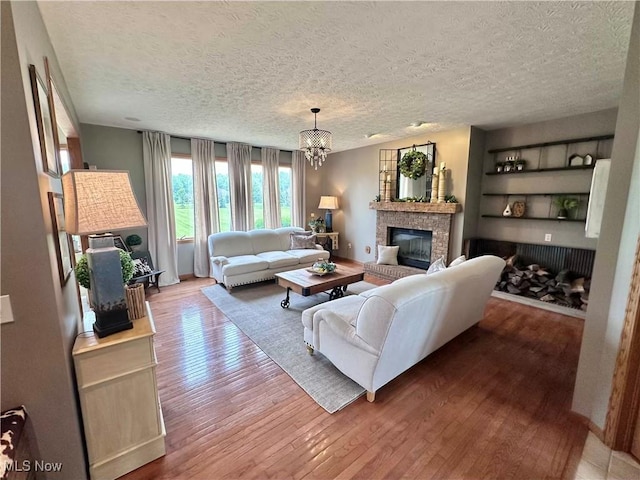 114 Mallard Creek Run, Lagrange, OH 44050 - living room with hardwood / wood-style floors, built in features, a chandelier, a fireplace, and a textured ceiling