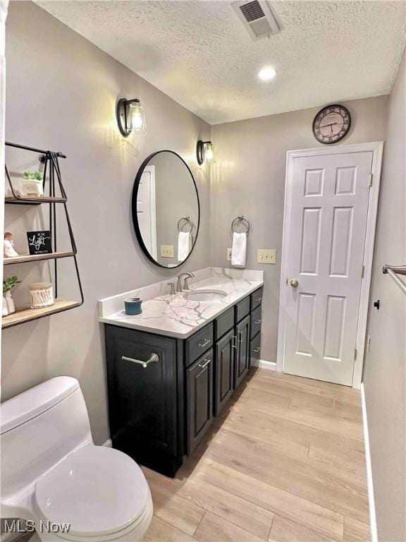 114 Mallard Creek Run, Lagrange, OH 44050 - bathroom featuring a textured ceiling, toilet, vanity, wood finished floors, and baseboards