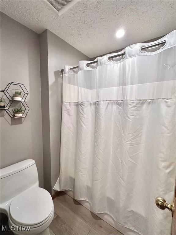 114 Mallard Creek Run, Lagrange, OH 44050 - full bath featuring a textured ceiling, wood finished floors, toilet, and curtained shower