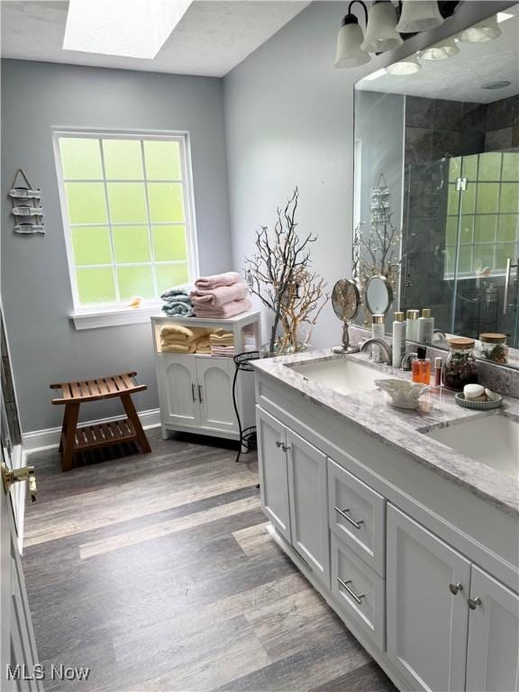 73 Falls River Dr Unit 6, Munroe Falls, OH 44262 - full bathroom with double vanity, wood finished floors, a stall shower, a skylight, and baseboards