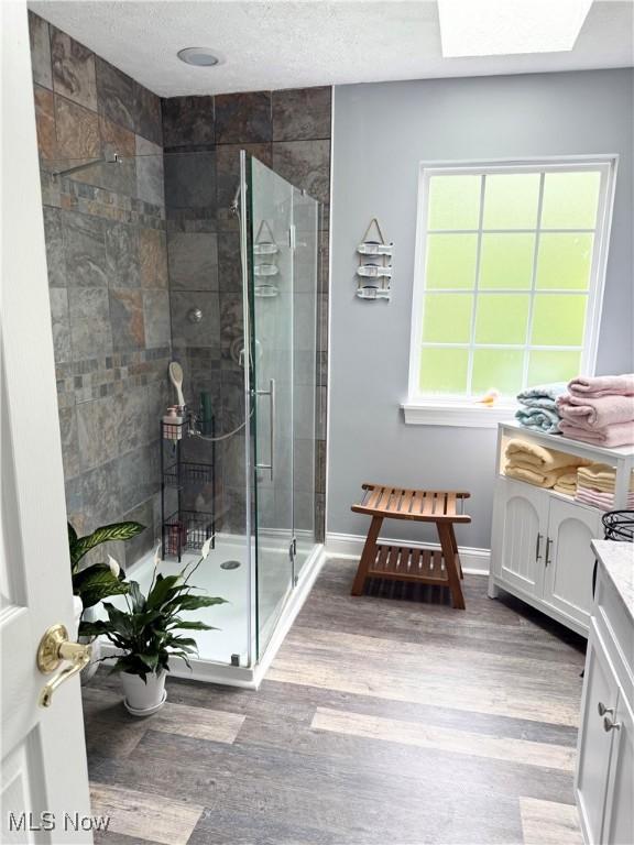 73 Falls River Dr Unit 6, Munroe Falls, OH 44262 - full bathroom with wood finished floors, a stall shower, vanity, baseboards, and a textured ceiling