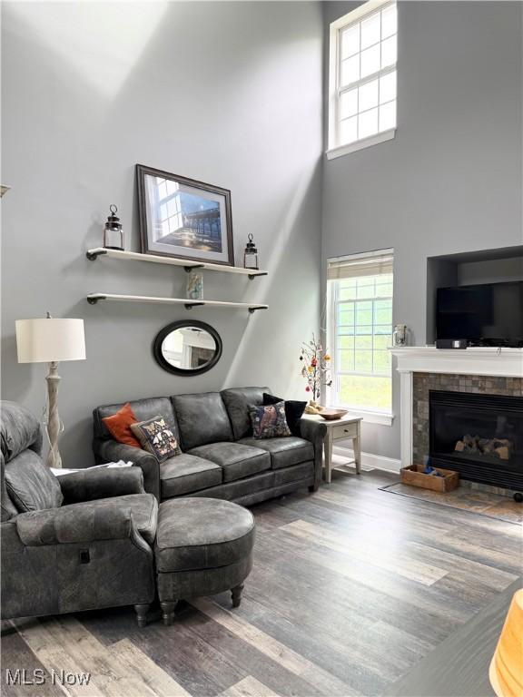73 Falls River Dr Unit 6, Munroe Falls, OH 44262 - living area featuring wood finished floors, a tiled fireplace, a towering ceiling, and baseboards