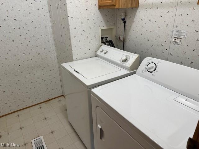 1569 Bogie Ln, Painesville, OH 44077 - laundry room with wallpapered walls, washer and clothes dryer, baseboards, and cabinet space