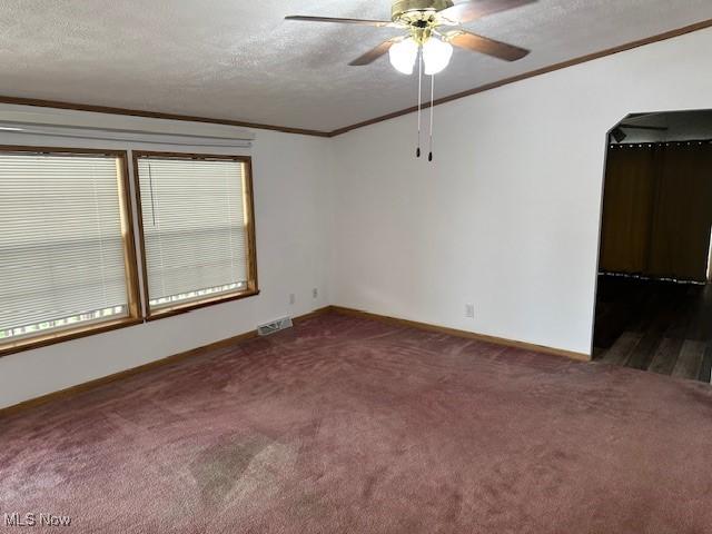1569 Bogie Ln, Painesville, OH 44077 - spare room featuring crown molding, dark carpet, ceiling fan, arched walkways, and baseboards