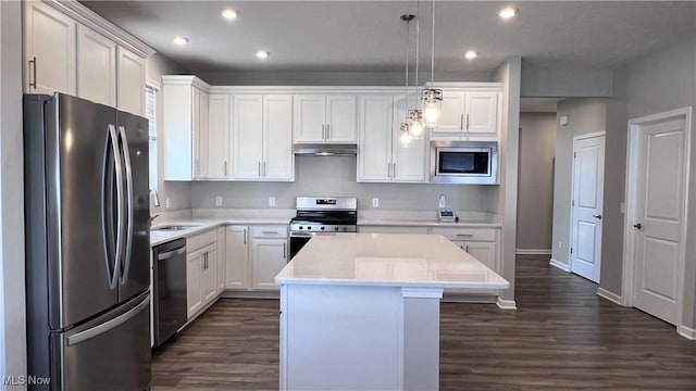 8099 Brookview Ln, Mentor, OH 44060 - kitchen featuring appliances with stainless steel finishes, under cabinet range hood, dark wood-type flooring, a center island, and recessed lighting