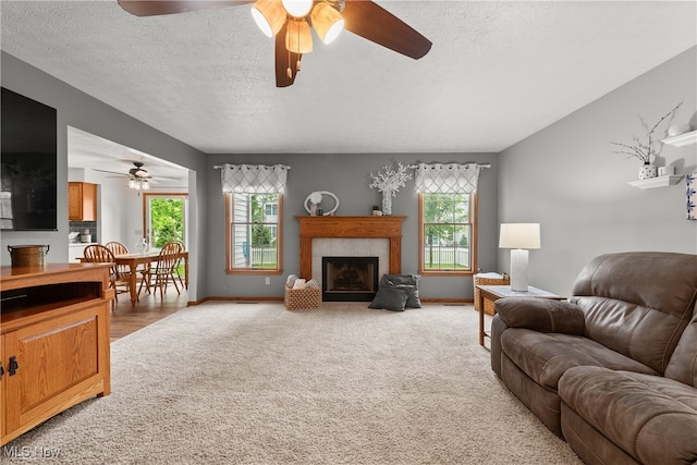 8373 Forest View Dr, Olmsted Falls, OH 44138 - living room featuring light carpet, a textured ceiling, ceiling fan, a fireplace, and baseboards