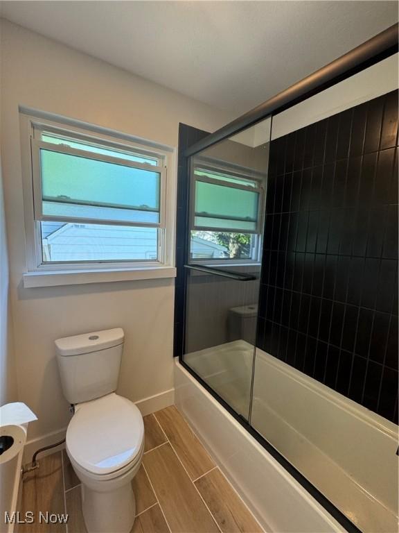 1267 Worton Blvd, Mayfield Heights, OH 44124 - bathroom featuring toilet, combined bath / shower with glass door, baseboards, and wood finish floors