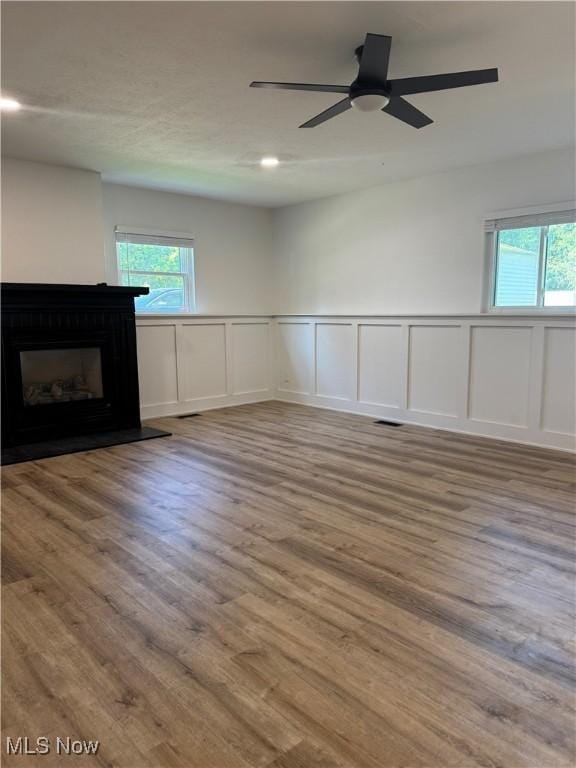 1267 Worton Blvd, Mayfield Heights, OH 44124 - unfurnished living room with a decorative wall, plenty of natural light, a fireplace, wainscoting, and wood finished floors