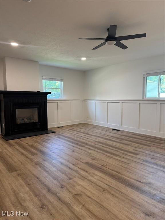 1267 Worton Blvd, Mayfield Heights, OH 44124 - unfurnished living room featuring a decorative wall, healthy amount of natural light, a fireplace, wood finished floors, and wainscoting