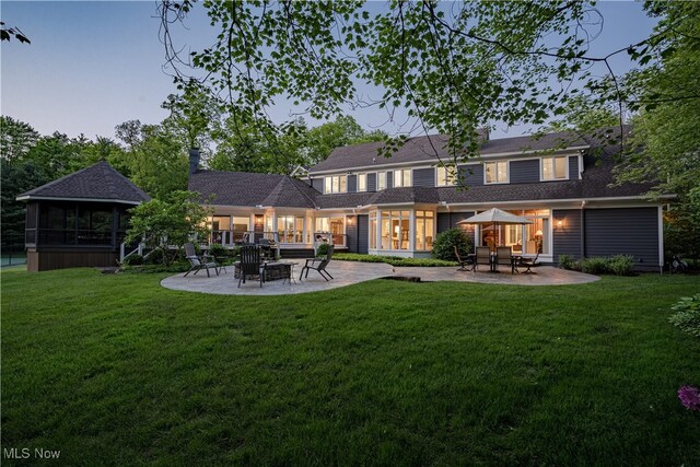 17980 Windy Lakes Cir, Chagrin Falls, OH 44023 - back of property at dusk with a patio, a fire pit, and a lawn