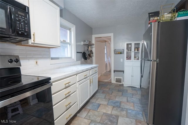 7811 Snow Rd, Parma, OH 44129 - kitchen with stainless steel appliances, white cabinets, tasteful backsplash, a textured ceiling, and stone finish floors