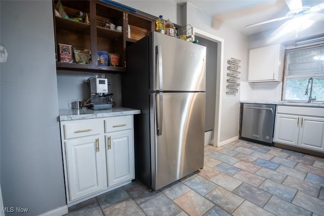 7811 Snow Rd, Parma, OH 44129 - kitchen with appliances with stainless steel finishes, light stone finish floors, a sink, baseboards, and white cabinets