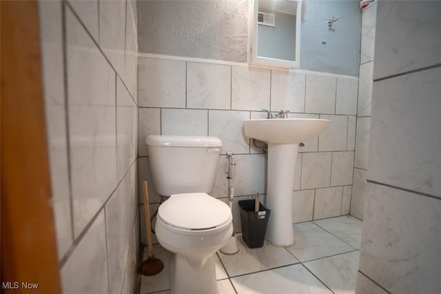 7811 Snow Rd, Parma, OH 44129 - bathroom featuring toilet, tile walls, a textured wall, and a sink
