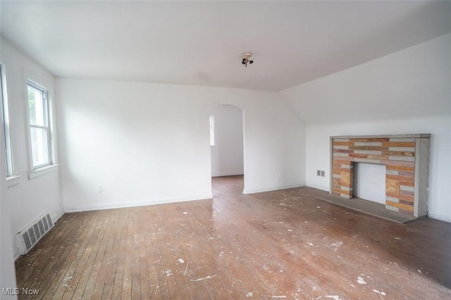 7811 Snow Rd, Parma, OH 44129 - unfurnished living room with wood-type flooring, arched walkways, a stone fireplace, and lofted ceiling