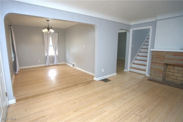 7811 Snow Rd, Parma, OH 44129 - empty room featuring arched walkways, light wood-style flooring, a chandelier, and stairs