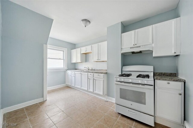 3331 Cedarbrook Rd, Cleveland Heights, OH 44118 - kitchen with white range with gas cooktop, under cabinet range hood, white cabinetry, baseboards, and dark stone counters