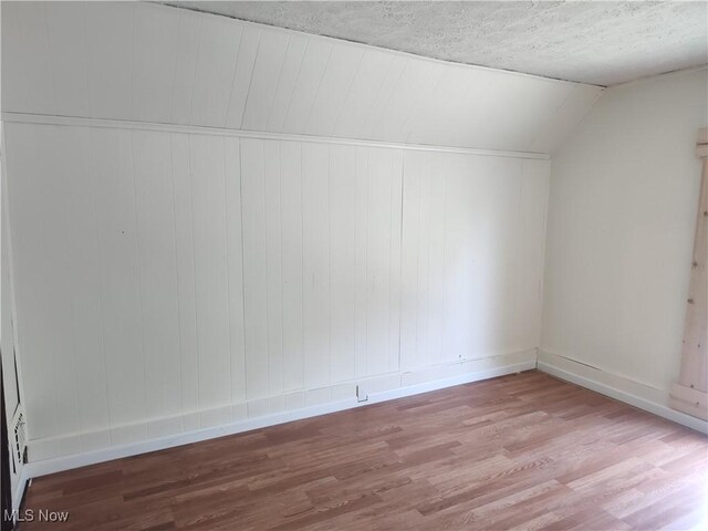 681 Madison St, Conneaut, OH 44030 - additional living space with wood finished floors, baseboards, vaulted ceiling, and a textured ceiling