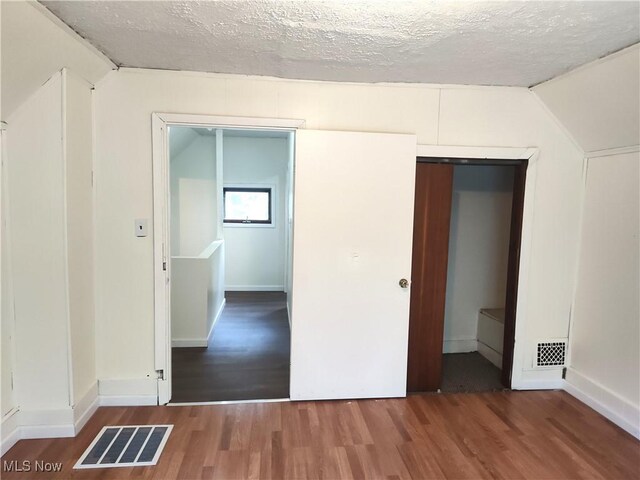 681 Madison St, Conneaut, OH 44030 - unfurnished bedroom featuring wood finished floors, a textured ceiling, lofted ceiling, and baseboards