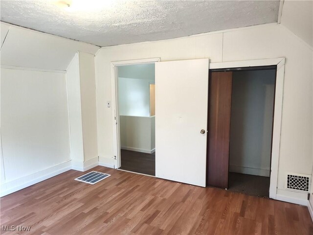 681 Madison St, Conneaut, OH 44030 - unfurnished bedroom with wood finished floors, lofted ceiling, a closet, a textured ceiling, and baseboards