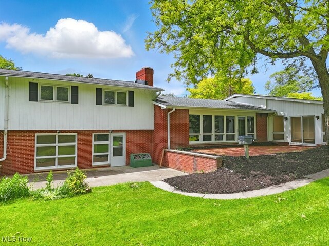 8049 Mccreary Rd, Broadview Heights, OH 44147 - rear view of house featuring a patio area, a chimney, a lawn, a sunroom, and brick siding