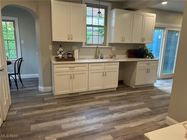 13707 Drexmore Rd, Shaker Heights, OH 44120 - kitchen featuring a sink, arched walkways, white cabinets, dark wood-style floors, and light countertops