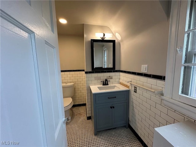 13707 Drexmore Rd, Shaker Heights, OH 44120 - half bathroom with tile walls, toilet, vanity, wainscoting, and tile patterned floors