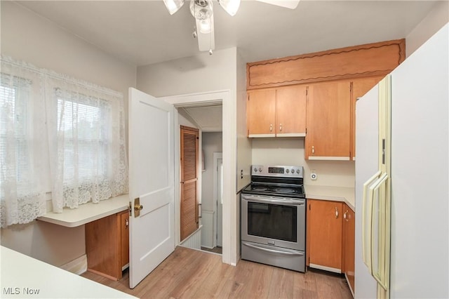 163 E Martin St, Amherst, OH 44001 - kitchen featuring stainless steel range with electric stovetop, freestanding refrigerator, light countertops, light wood-style floors, and ceiling fan