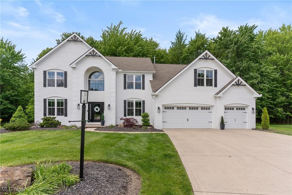 21492 Brookfield Pl, Strongsville, OH 44149 - view of front facade with concrete driveway, a front lawn, an attached garage, a shingled roof, and stucco siding