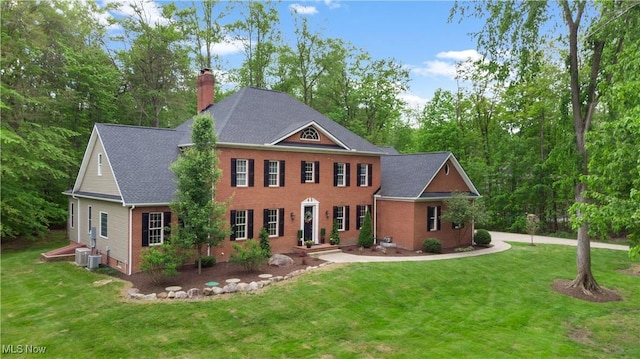 11665 Ascot Ln, Chagrin Falls, OH 44023 - view of front facade featuring a chimney, a front lawn, brick siding, and cooling unit