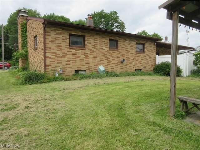 163 N Chestnut St, Linesville, PA 16424 - view of home's exterior with a chimney, a lawn, and brick siding