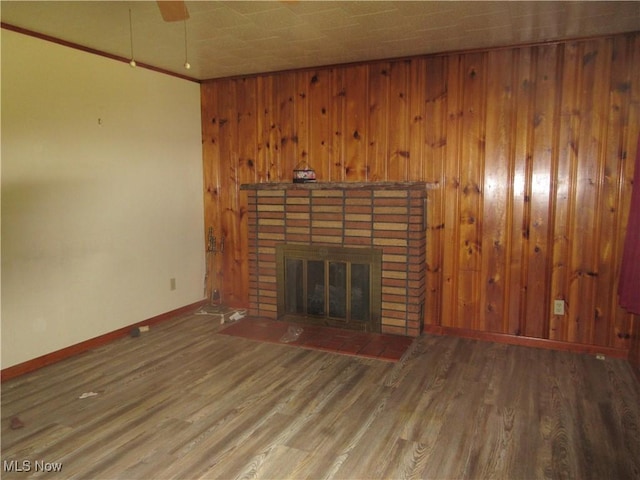 163 N Chestnut St, Linesville, PA 16424 - unfurnished living room featuring baseboards, a fireplace, wood finished floors, and wooden walls