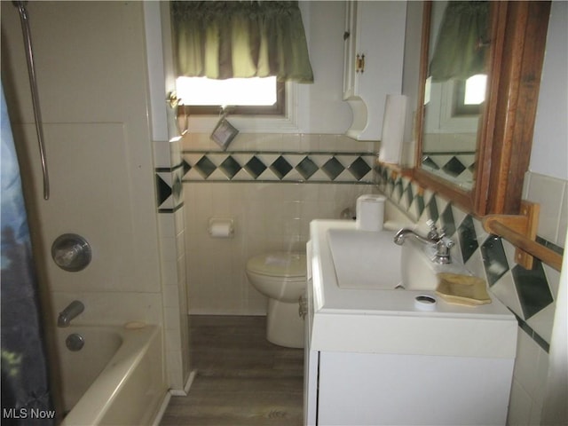 163 N Chestnut St, Linesville, PA 16424 - bathroom with vanity, wood finished floors, toilet, shower / bathtub combination with curtain, and tile walls
