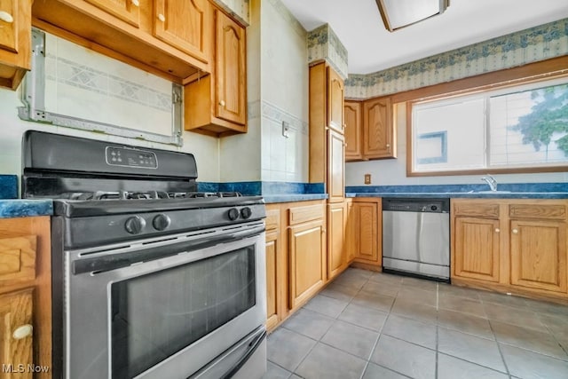 1586 E 86th St, Cleveland, OH 44106 - kitchen featuring stainless steel appliances, light tile patterned flooring, a sink, and dark countertops