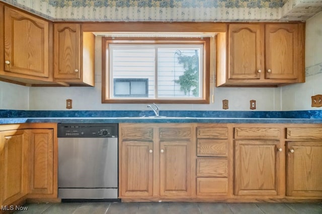 1586 E 86th St, Cleveland, OH 44106 - kitchen featuring stainless steel dishwasher, dark countertops, a sink, light tile patterned floors, and brown cabinetry