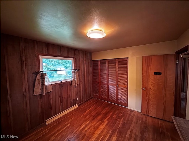 2325 Stewart Dr NW, Warren, OH 44485 - unfurnished bedroom featuring wood walls, dark wood-style flooring, a closet, and baseboards