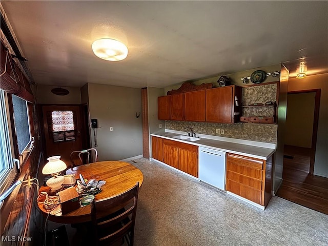 2325 Stewart Dr NW, Warren, OH 44485 - kitchen with white dishwasher, a sink, brown cabinetry, baseboards, and decorative backsplash