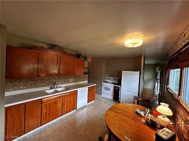 2325 Stewart Dr NW, Warren, OH 44485 - kitchen with white appliances, a sink, brown cabinets, light countertops, and backsplash