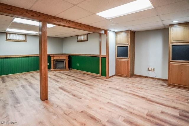 2410 Rohrer St NW, North Canton, OH 44720 - basement featuring a paneled ceiling, light wood-type flooring, a fireplace, and a wainscoted wall