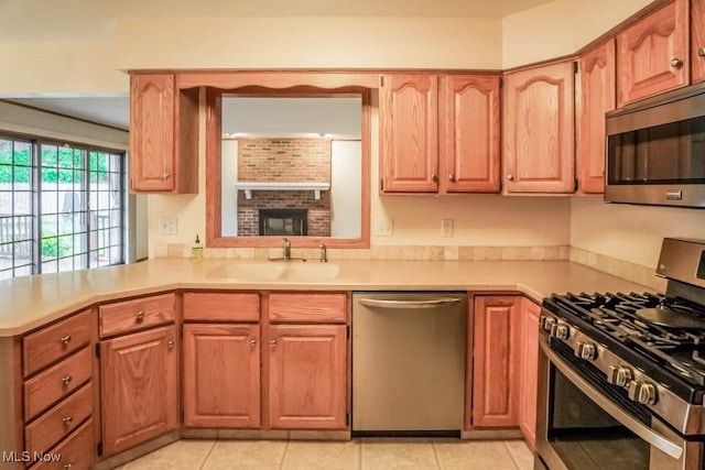 2410 Rohrer St NW, North Canton, OH 44720 - kitchen with appliances with stainless steel finishes, a sink, light countertops, light tile patterned floors, and a peninsula