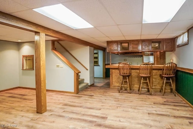 2410 Rohrer St NW, North Canton, OH 44720 - dining area with light wood-style floors, bar, stairway, a drop ceiling, and baseboards