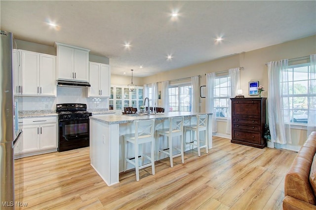 1572 Gate House St NE, Canton, OH 44721 - kitchen with black range with gas cooktop, freestanding refrigerator, light wood-style floors, recessed lighting, and a kitchen island with sink
