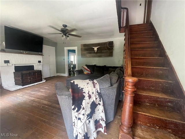 2743 Cow Creek Rd, Saint Marys, WV 26170 - living area with ceiling fan, stairs, hardwood / wood-style flooring, a brick fireplace, and baseboards