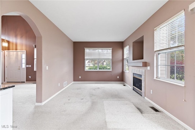 7284 Forest Cove Ln, Northfield, OH 44067 - unfurnished living room featuring light carpet, a tile fireplace, baseboards, and arched walkways