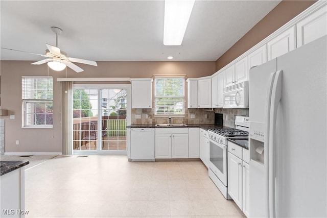 7284 Forest Cove Ln, Northfield, OH 44067 - kitchen featuring white appliances, white cabinets, decorative backsplash, a sink, and a ceiling fan