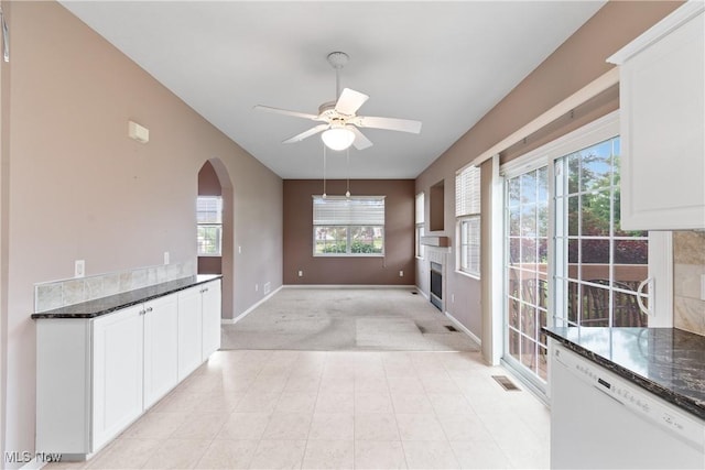 7284 Forest Cove Ln, Northfield, OH 44067 - unfurnished living room with light colored carpet, baseboards, ceiling fan, arched walkways, and a fireplace
